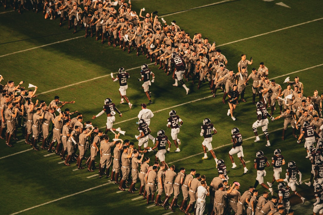 College football players running through a crowd tunnel onto the field